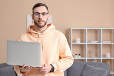 Oturma odasında dizüstü bilgisayar ile yakışıklı adam