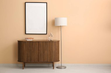 İçinde lamba ve bej duvarda boş poster olan çekmeceler.