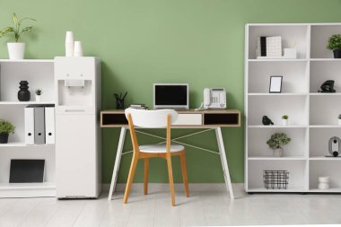 Modern su soğutucusu, çalışma alanı ve raf üniteleri olan şık bir ofis.