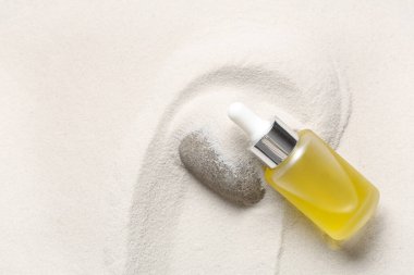 Dekoratif taş ve şişe arka plan olarak beyaz kum üzerinde kozmetik ürün