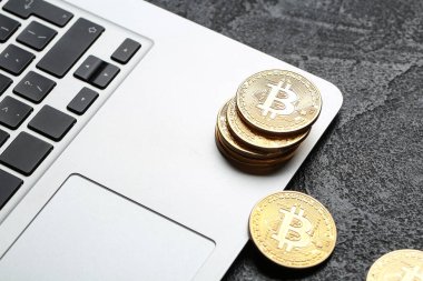 Koyu arkaplanda dizüstü bilgisayarı olan altın bitcoinler