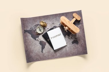 Pasaportlar, ahşap uçak, pusula ve renk arkaplanındaki dünya haritası