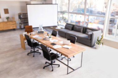 Masa, kanepe ve projektör ekranlı konferans salonunun bulanık görüntüsü