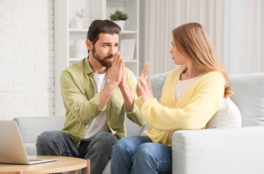 Kocasını evdeki kanepede affetmeyi reddeden genç bir kadın.