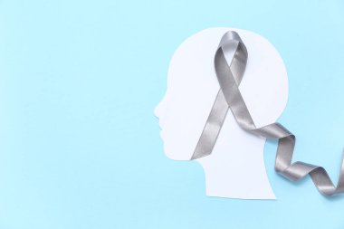 Mavi arka planda gri farkındalık kurdelesi olan kağıt insan kafası. Beyin kanseri kavramı