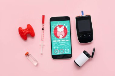 Tiroit bezi modelli cep telefonu, glukometre ve pembe arka planda insülin. Endokrinoloji kavramı