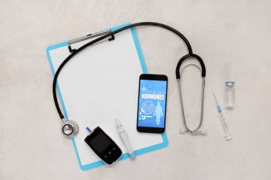 Glukometre, steteskop ve arka planda pano olan cep telefonu. Endokrinoloji kavramı