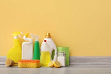 Sarı duvarın yanında temizlik malzemeleri var.