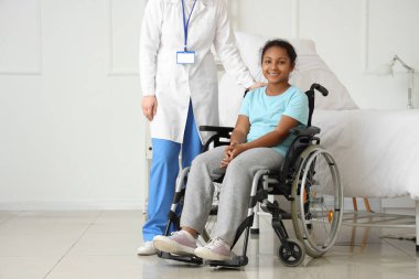 Genç Afro-Amerikan kız tekerlekli sandalyede, hastanede doktorla.