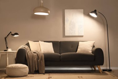 Modern oturma odasının içinde rahat bir kanepe ve parıldayan lambalar.