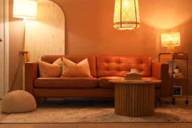 Rahat kanepesi, sehpası ve parlak lambaları olan şık bir oturma odası.