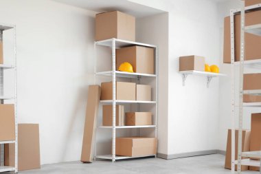 İçinde raf ünitesi, karton kutular ve başlıklar olan hafif deponun içi.