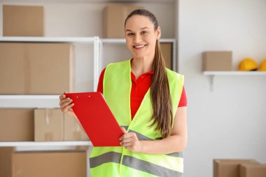 Depoda panosu olan kadın işçi.