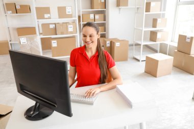 Depodaki masada bilgisayarla çalışan kadın işçi.