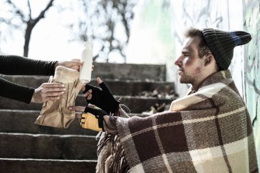 Evsiz bir adam sokakta sütle ekmek yiyor.