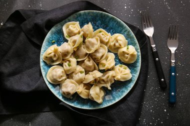 Siyah arkaplanda yeşil soğanlı lezzetli haşlanmış hamur köfteleri.