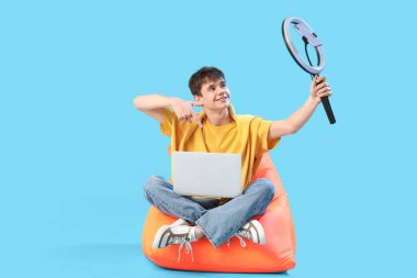 Mavi arkaplanda dizüstü bilgisayarı olan genç blogcu