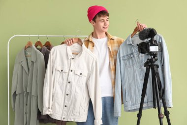 Kot ceketli genç blog yazarı yeşil arkaplan üzerine video kaydediyor