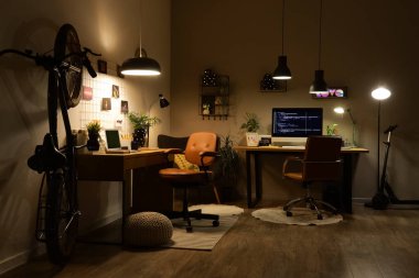 Geceleri masaları, bisikletleri ve parlayan lambaları olan karanlık programcılar ofisi.