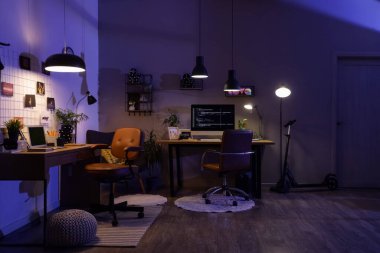 Geceleri masaları ve parlayan lambaları olan karanlık programcı ofisinin içinde.