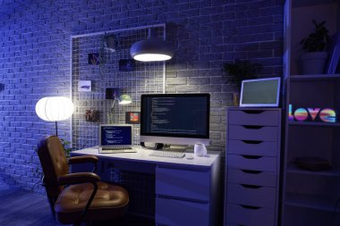 Geceleri karanlık programcı bürosunun çalışma odası, çivi tahtası ve parlayan lambaları.