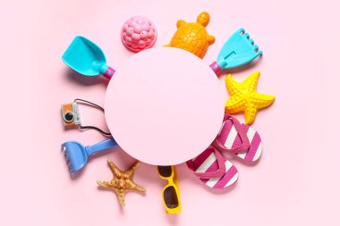 Boş kağıt çarşaf, plaj kumları ve pembe arka plandaki çocuklar için plaj aksesuarlarından yapılmış çerçeve.