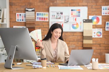 Ofiste dizüstü bilgisayar ve renk paletleri ile çalışan güzel bir tasarımcı