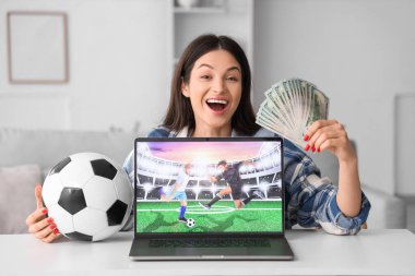 Evdeki spor bahsini kazandıktan sonra parası ve futbol topu olan mutlu genç bir kadın.