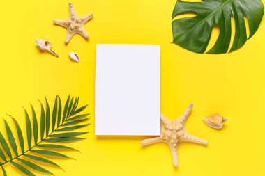 Çerçeve boş kağıt çarşaf, deniz kabukları, deniz yıldızları ve sarı arka planda tropikal yapraklardan yapılmıştır.