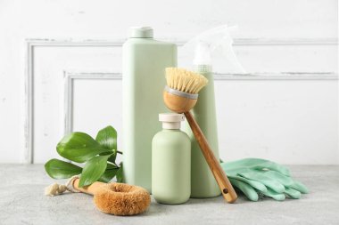 Işık duvarının yanındaki masada bitki dalı olan doğal temizlik malzemeleri.