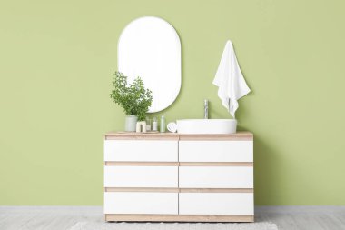 Banyonun içinde yeşil dallar ve lavabo var.