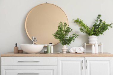 Lavabonun yanında yeşil dalları olan bir banyo.