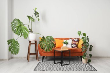 İçinde Monstera bitkileri, kanepe ve masa olan bir oturma odası.