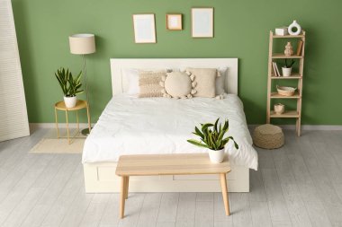 Yatak odasının içinde yatak, bank ve Sansevieria bitkileri var.