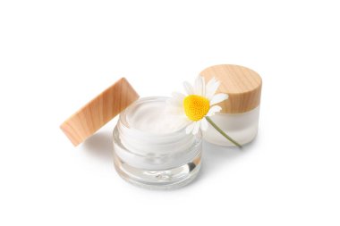 Beyaz arka planda doğal krema kavanozları ve papatya çiçeği.