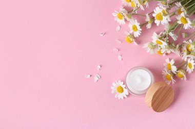 Doğal krema kavanozu ve pembe arka planda güzel papatya çiçekleri.