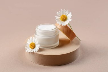 Dekoratif podyum, kahverengi arka planda papatya çayı ve çiçek kavanozu.