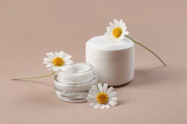 Kavanozlar dolusu papatya çayı ve kahverengi arka planda çiçekler.