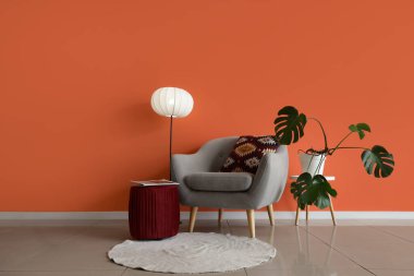 Gri koltuğu, lambası ve Monstera bitkisi olan oturma odasının içinde.