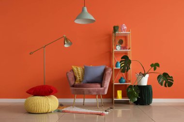 İçinde pembe koltuk, raf ünitesi ve lambalar olan oturma odası.