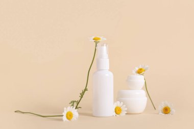 Bej arka planda papatya çayı olan şişe ve kozmetik ürünleri.