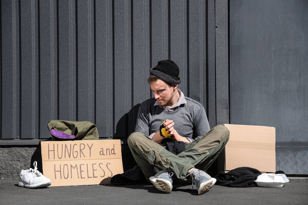 Homeless man with cardboard sitting on street