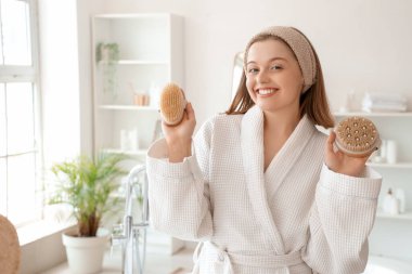 Banyoda masaj fırçaları olan genç bir kadın.