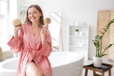 Banyoda masaj fırçaları olan genç bir kadın.