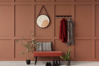 Pembe bankları, paltoları ve aynaları olan şık bir koridor.