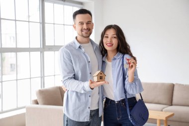 Yeni dairelerinde anahtar ve ev figürleri olan genç bir çift.