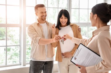 Emlakçı, yeni evden hamile çifte oda anahtarı veriyor.