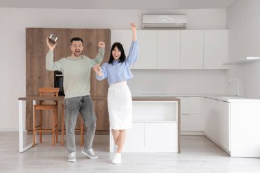 Ev modeli ve mutfaktaki yeni dairelerinin anahtarlarıyla mutlu genç bir çift.