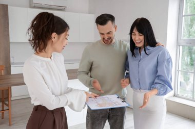 Mutfakta ev planına bakan bir çifti olan kadın emlakçı.