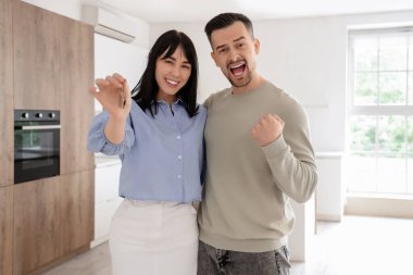 Mutfaktaki yeni dairesinin anahtarı olan mutlu genç bir çift.